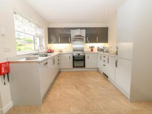 a kitchen with white cabinets and a tile floor at Cae Glas in Pwllheli