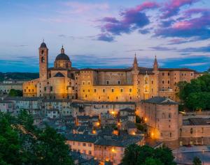 un gran castillo sentado en la cima de una ciudad por la noche en A casa di Matisse - appartamento vacanze en Urbino