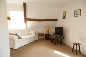 a living room with a white couch and a television at A la Bergerie in Honfleur