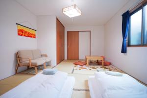 Habitación con 2 camas y una silla. en TOKIHouse 京都時光 en Kioto