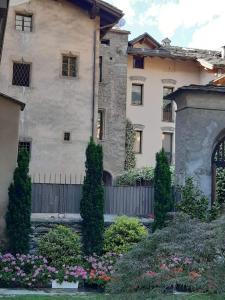 un grand bâtiment avec une clôture et quelques buissons et fleurs dans l'établissement Casa di Sant'Anselmo - La Corte - CIR VDA AOSTA 0193, à Aoste