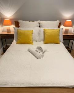 una cama blanca con dos almohadas amarillas y dos lámparas en Cardiff Home, en Cardiff