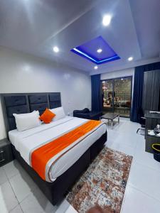 a bedroom with a large bed with an orange blanket at De Rigg Place Embassy in Lagos