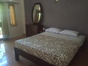 a bedroom with a bed with a mirror on the wall at Belong Bunter Homestay in Uluwatu