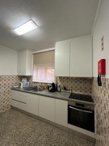cocina con armarios blancos y fogones en CASA SOPHIE - Alojamento,Dormitório,Casa de Férias, en Ansião