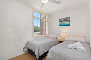 two beds in a room with a window at Little Hut Unit 3 20 Kurrawa Close in Nelson Bay