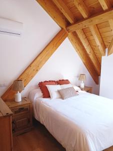 sypialnia z białym łóżkiem i drewnianym sufitem w obiekcie Duplex El Refugio de La Bolera w mieście Arroyo Frio