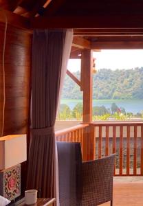 a room with a balcony with a view of a lake at BUYAN LODGE lake view villa in Bedugul