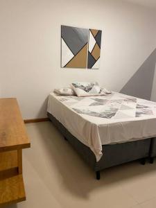 1 cama en un dormitorio con una pintura en la pared en Apartamento com vista para as montanhas e natureza, en Petrópolis