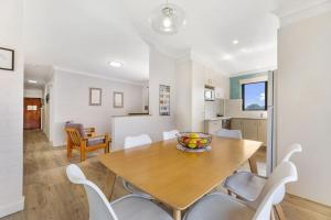 uma cozinha e sala de jantar com uma mesa de madeira e cadeiras em Apollo Unit 21 1st Floor em Narooma