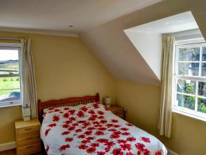 a bedroom with a bed with red flowers on it at Stonebank House in Lamberton