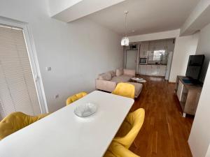 a living room with a white table and yellow chairs at Skopje Eluxory Apartments in Skopje