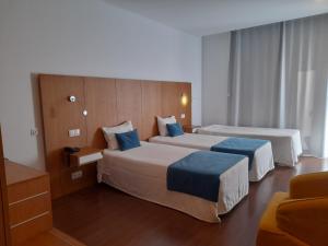 um quarto de hotel com duas camas com almofadas azuis em Belmonte Sinai Hotel em Belmonte