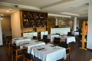 uma sala de jantar com mesas e cadeiras brancas num restaurante em Belmonte Sinai Hotel em Belmonte