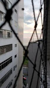 a view through a wire fence of a building at Studio Frente à Praia Boqueirão in Santos