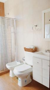a white bathroom with a toilet and a sink at Casa con pileta en Paso de la Patria in Paso de la Patria