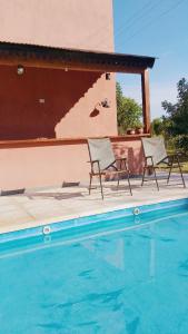 two chairs sitting next to a swimming pool at Casa con pileta en Paso de la Patria in Paso de la Patria