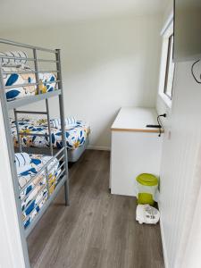 a room with two bunk beds and a desk at Athenree Hot Springs & Holiday Park in Waihi Beach