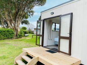 a tiny house with a porch and a wooden deck at Athenree Hot Springs & Holiday Park in Waihi Beach