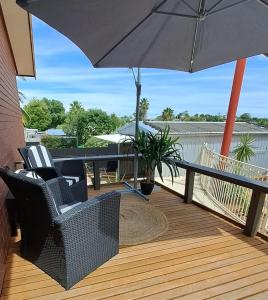 a patio with chairs and an umbrella on a deck at Cummins Cottage in Broken Hill