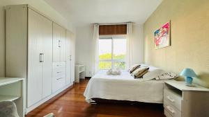 a white bedroom with a bed and a window at Ótimo Apto Shopping Iguatemi in Porto Alegre