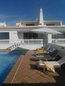 a pool with chairs and a lighthouse on a house at Villa Castro Marim in Castro Marim