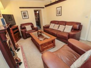 a living room with leather couches and a coffee table at Victoria Cottage in Amble