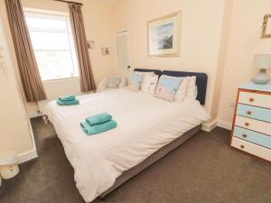 a bedroom with a large white bed with two towels on it at Victoria Cottage in Amble