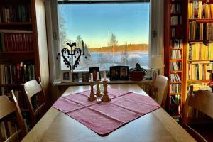 a dining room table with a view of a lake at Stort hus med trädgård - sjötomt med egen båt in Västra Ryd