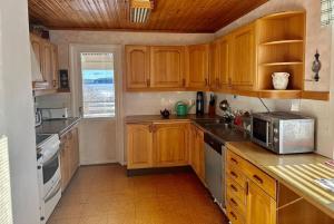 een keuken met houten kasten en een magnetron bij Stort hus med trädgård - sjötomt med egen båt 