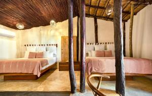 a bedroom with two beds and a wooden ceiling at Alquimia Hotel Boutique in Tulum