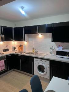 uma cozinha com armários pretos e uma máquina de lavar roupa em Shelly's Place em Glasgow