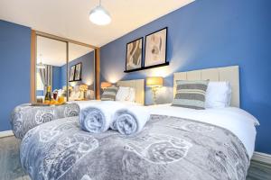 米爾頓凱恩斯的住宿－Luxury 4 Bedroom House - Close to M1 - Free Parking, Fast Wifi, SmartTV with Netflix by Yoko Property，一间卧室设有两张带蓝色墙壁和镜子的床。