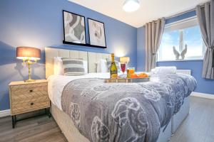 a bedroom with a large bed with blue walls at Luxury 4 Bedroom House - Close to M1 - Free Parking, Fast Wifi, SmartTV with Netflix by Yoko Property in Milton Keynes