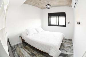 a bedroom with a bed in a white room at Depto. en Costanera frente al rio 2 a 4 personas in San Nicolás de los Arroyos