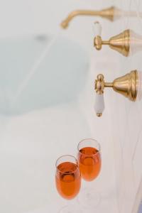 dos vasos de zumo de naranja sentados en el mostrador del baño en Amberesque B&B, en Rutherglen