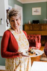 a woman is holding a plate of food at Amberesque B&B in Rutherglen