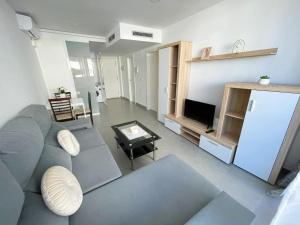 ein Wohnzimmer mit einem blauen Sofa und einem TV in der Unterkunft Apartamentos Novacala Benidorm in Cala de Finestrat