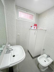 a white bathroom with a sink and a toilet at Apartamentos Novacala Benidorm in Cala de Finestrat