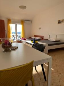 a room with two beds and a table and chairs at Apartments Badnje in Dramalj