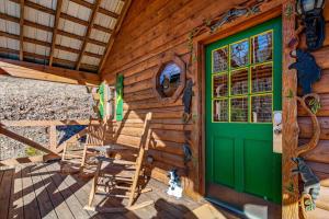 eine Hütte mit grüner Tür und Stühlen auf einer Veranda in der Unterkunft The Mountain Farmer in Sevierville