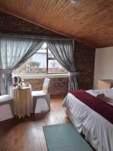 a bedroom with a bed and a table and a window at Hamba Kancane Ma-Africa Guest House in Graskop +101 photos