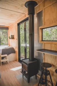a fireplace in a tiny house with a bedroom at CABN Off Grid Cabins Barossa in Seppeltsfield