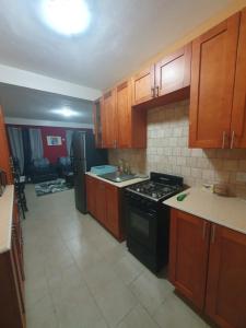 eine Küche mit Holzschränken und einem Backofen mit schwarzem Kochfeld in der Unterkunft Lovely 2 Bedroom Apartment with shared pool in Roseau