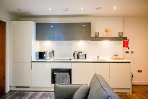 Luxury 2 bedroom apartment في برمنغهام: مطبخ مع دواليب بيضاء واريكة في الغرفة