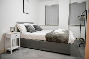 Luxury 2 bedroom apartment في برمنغهام: غرفة نوم مع سرير مع منضدة وطاولة بيضاء