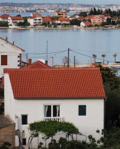 ein weißes Haus mit orangefarbenem Dach neben dem Wasser in der Unterkunft Seaside holiday house Lukoran, Ugljan - 20384 in Lukoran