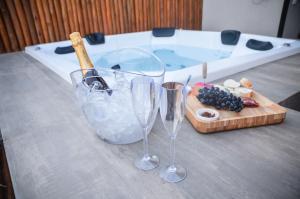 uma mesa com dois copos de vinho e uma tábua de cortar com uma banheira de hidromassagem em Vila Astra - jacuzzi privativa, natureza e conforto em Alto Paraíso de Goiás