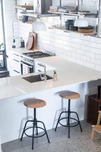a kitchen with two bar stools and a sink at Stylish, comfortable and pet friendly home in the heart of Kensington in Norwood
