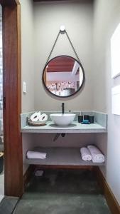 La salle de bains est pourvue d'un lavabo et d'un miroir. dans l'établissement Vila Astra - jacuzzi privativa, natureza e conforto, à Alto Paraíso de Goiás